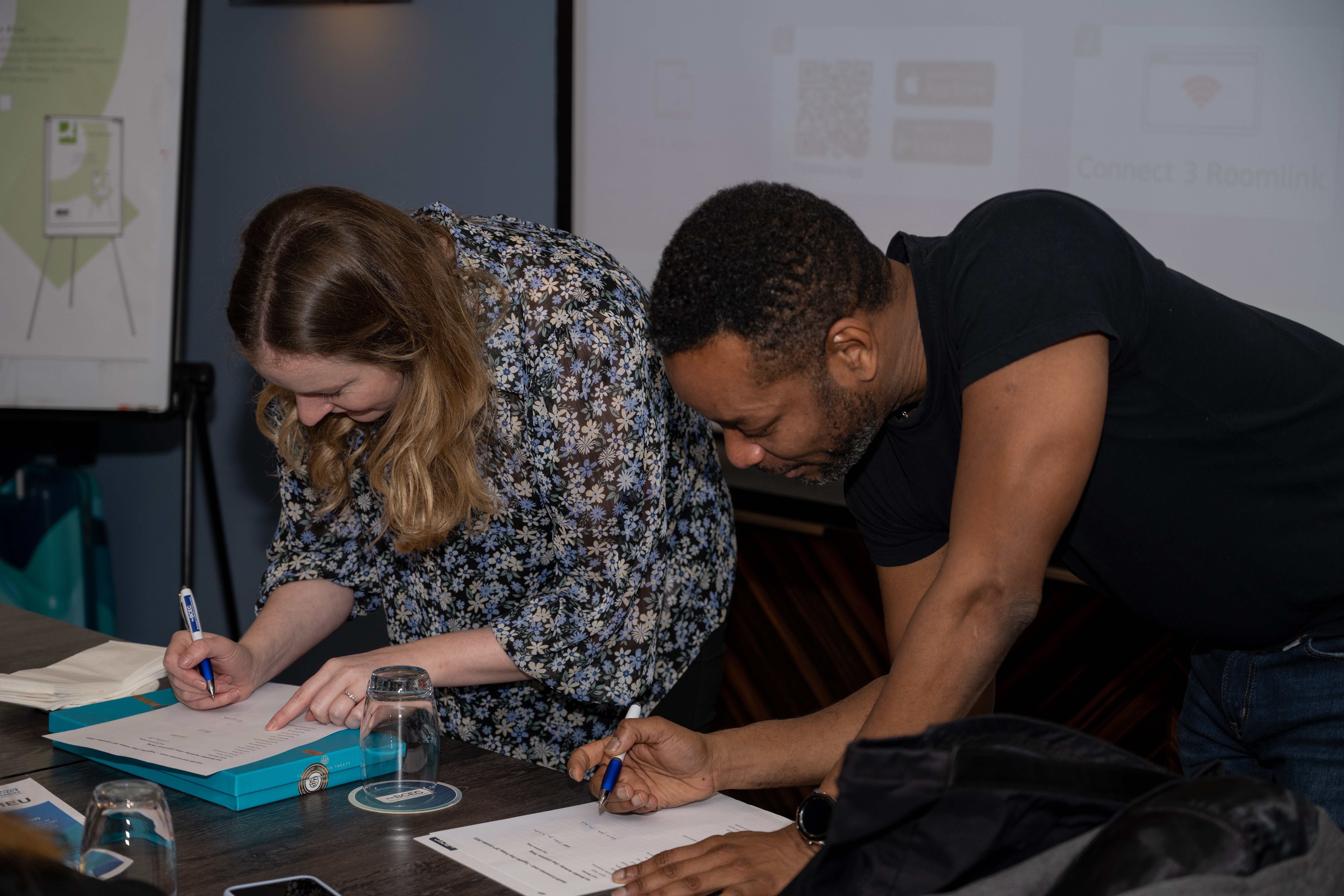 Two people at a desk writing